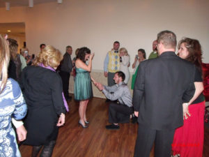 A man kneeling while proposing to a woman